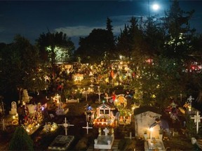Candles illuminate children’s tombs in the San Gregorio cemetery during Day of the Dead festivities on the outskirts of Mexico City, late Saturday, Nov. 1, 2015. In a tradition that coincides with All Saints’ Day and All Souls’ Day on Nov. 1 and 2, families decorate the graves of departed relatives with marigolds and candles, and spend the night in the cemetery, eating and drinking as they keep company with their deceased loved ones. At this cemetery, families pay a special tribute to children who have died, on the night of Oct. 31 into the morning of Nov. 1. The following night, families keep vigil at the tombs of adults.