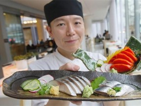 Chef Taka Omi of The Raw Bar at the Fairmont Pacific Rim hotel in Vancouver holds a plate of mackerel and sardine sashimi, and wild sockeye salmon sashimi.