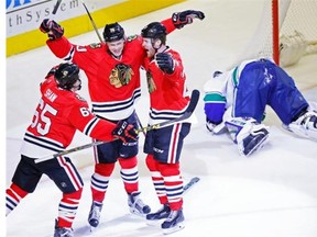 Chicago Blackhawks center Dennis Rasmussen (70) celebrates his goal past Vancouver Canucks goalie Ryan Miller (30) with teammates Andrew Shaw (65) and Bryan Bickell (29) during the third period of an NHL hockey game in Chicago, Sunday, Dec. 13, 2015. Chicago won 4-0.