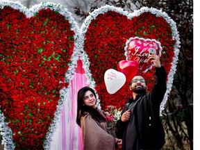 A couple take ‘selfie’ in front of a giant heart-shaped bouquet display by a vendor to attract customers on Valentine’s Day, Sunday, Feb. 14, 2016. Celebrating Valentine’s Day is considered un-Islamic by some in Pakistan, but many still buy flowers and exchange gifts with others.