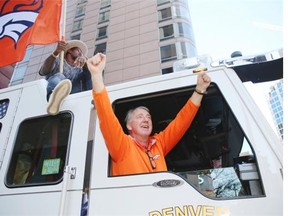 Denver Broncos President Joe Ellis waves to the crowd from the front seat of a fire engine while Von Miller waves a Broncos flag during a Super Bowl victory parade, Tuesday, Feb. 9, 2016, in Denver.