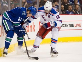 Derek Dorsett #51 of the Vancouver Canucks and Marc Staal #18 of the New York Rangers battle of the puck behind the net during the first period in NHL action on December, 13, 2014 at Rogers Arena in Vancouver, British Columbia, Canada.