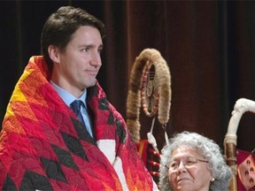 An elder stands beside Prime Minister Justin Trudeau after he was presented with a blanket at the Assembly of First Nations Special Chiefs Assembly in Gatineau, Que., on Tuesday.