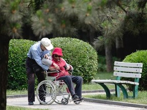 An elderly man helps a woman on a wheelchair at a park in this undated file photo.