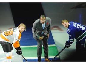 Former Vancouver Grizzlies basketball player Shareef Abdur-Rahim takes part in a special puck drop celebrating 20 years since the opening of Rogers Arena -at the start of the Vancouver Canucks game against the Philadelphia Flyers  Claude Giroux Flyers Captain (left) with  Henrik Sedin 33,  (r) take part in the special face off.