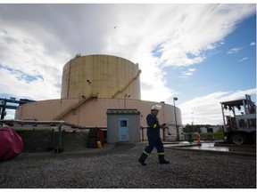 Members of the Tsawwassen First Nation in suburban Vancouver will vote next month on plans for a liquefied natural gas export facility on their lands near Delta. In this file photo: A FortisBC employee walks past a storage tank at the existing FortisBC Tilbury LNG facility before the groundbreaking for an expansion project in Delta, B.C., on Tuesday October 21, 2014.