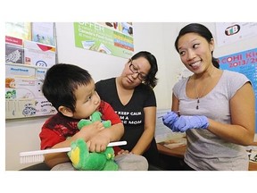 Ian Tom-Henry, 3, might need a little more coaxing as Pamela Poon, right, a dental hygienist for the First Nations Health Authority, and community aide Angel Henry attend to him at the Pauquachin band medical office.