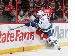 Bo Horvat #53 of the Vancouver Canucks checks Mark Borowiecki #74 of the Ottawa Senators as they both try to get the loose puck.