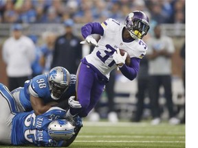 Jerick McKinnon #31 of the Minnesota Vikings is tackled by Devin Taylor #98 and Stephen Tulloch #55 of the Detroit Lions in the second quarter at Ford Field on October 25, 2015 in Detroit, Michigan.