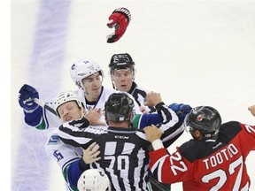 New Jersey Devils right wing Jordin Tootoo fights with Vancouver Canucks winger Derek Dorsett (left) while trying to get at Alex Burrows during the second period of their NHL  game on Sunday in Newark, N.J.