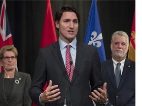 Ontario Premier Kathleen Wynne and Quebec Premier Philippe Couillard look on as Prime Minister Justin Trudeau speaks during a news conference following the First Ministers meeting at the Canadian Museum of Nature in Ottawa on Monday, Nov. 23, 2015.