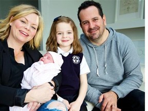 Kate Austin-Rivas holding new baby Scarlett at age one month, with husband Didier Rivas and daughter Elle. Scarlett  was born to a surrogate mother.