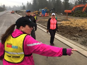 Crystal Pudsey, one of the fun leaders with the W.C. Blair Sun Run InTraining clinic, directs learn-to-run participants through a construction zone in growing Langley.