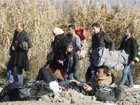 Migrants and refugees walk toward the border with Serbia, while other migrants, who were not allowed to cross into Serbia, lie on the ground awaiting for a solution, near the village of Tabanovce, in northern Macedonia, Thursday.