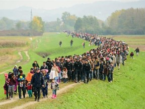 Migrants and refugees walk toward a refugee center after crossing the Croatian-Slovenian border near Brezice on Friday. More than 12,600 migrants arrived in Slovenia over a 24-hour period, police said.