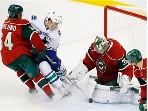 Minnesota Wild goalie Darcy Kuemper, right,  stops a shot by Vancouver Canucks center Bo Horvat, center, as Wild center Mikael Granlund (64), of Finland, tries to keep Horvat off the puck during the first period of an NHL hockey game in St. Paul, Minn., Tuesday, Dec. 15, 2015.