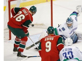 Minnesota Wild left wing Thomas Vanek (26), of Austria, scores on Vancouver Canucks goalie Ryan Miller, right, during the first period of an NHL hockey game in St. Paul, Minn., Tuesday, Dec. 15, 2015.