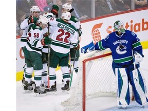 Minnesota Wild right wing Justin Fontaine (14) celebrates his goal with his teammates as Vancouver Canucks goalie Jacob Markstrom (25) looks on during second period NHL action in Vancouver, B.C. Monday, Feb. 15, 2016.