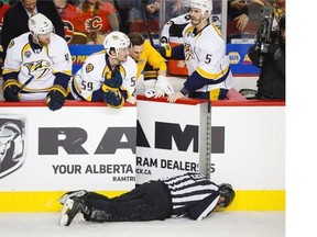 Nashville Predators players look over the bench at linesman Don Henderson after he was hit by Calgary Flames defenceman Dennis Wideman during the second period of their National Hockey League game in Calgary on Wednesday, Jan. 27, 2016.