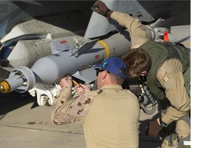An Air Weapons Systems Technician and a pilot inspect a CF-18 Hornet fighter jet before the next mission at Camp Patrice Vincent during Operation Impact on January 14, 2015.
