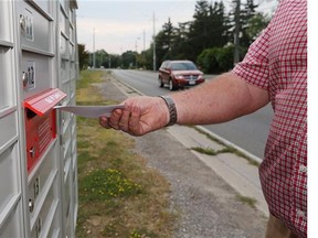FILE — A man places mail into a mailbox.
