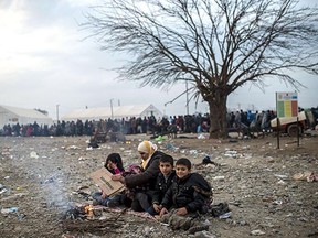 A migrant woman and her children keep warm around a bonfire as they wait to enter a registration camp, on November 21, 2015, near Gevgelija, after crossing the Macedonian-Greek border. Serbia and Macedonia, which lie on the main migrant route to northern Europe, have begun restricting the entry of refugees to just those from certain countries, the UN refugee agency said on November 19.
