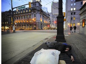 A homeless man attempts to stay warm as the cool weather settles in downtown Vancouver .