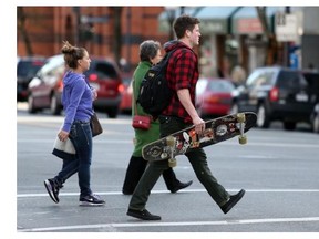 A skateboarder walks across the intersection at Douglas and Fort streets in Victoria.