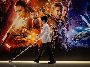 A cleaner walks past a poster advertising "Star Wars: The Force Awakens" in Hong Kong on December 17, 2015.