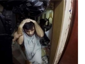 This image made from video taken from a helmet camera, shows U.S. and Iraqi special forces searching prisoners inside a makeshift prison in the town of Huwija.