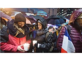 People attend a vigil outside the French consulate in Montreal, Friday for those killed in the Paris attacks.