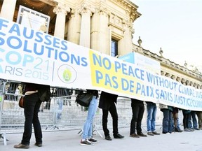 People display a banner reading which translates as “false solutions COP21 No peace without climate justice” in front of the “Solutions COP21” exhibition at the Grand Palais in Paris on December 4, 2015 as  part of the COP 21, the United Nations conference on climate change. More than 150 world leaders are meeting under heightened security, for the 21st Session of the Conference of the Parties to the United Nations Framework Convention on Climate Change COP21/CMP11) from November 30 to December 11.