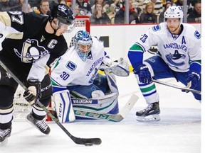 Pittsburgh Penguins’ captain Sidney Crosby looks to get off a shot in front of Vancouver Canucks goalie Ryan Miller and defenceman Alexander Edler during the second period of an NHL hockey game in Pittsburgh on Saturday.