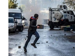 A protester runs away as Turkish riot police fire tear gas during a demonstration in Diyarbakir to denounce security operations against Kurdish rebels.