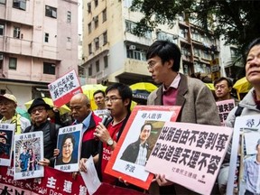 Protesters hold up missing person notices of (L-R) Mighty Current publisher of books critical of China company’s general manager Lui Bo and colleagues Cheung Jiping, Gui Minhai, Lee Bo and Lam Wing-kei as they walk towards China’s Liaison Office in Hong Kong on January 3, 2016.