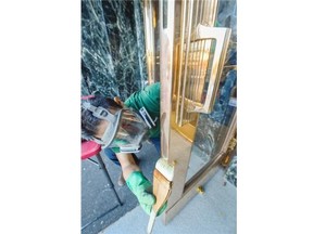 Rene Rodriguez of Shineguard Industries applies a solution to the brass doors at Vancouver City Hall that will keep them looking polished for at least a year.