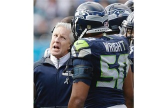 Seattle Seahawks head coach Pete Carroll speaks with Seattle Seahawks outside linebacker K.J. Wright (50) on the sidelines during the first half of an NFL divisional playoff football game against the Carolina Panthers, Sunday, Jan. 17, 2016, in Charlotte, N.C.
