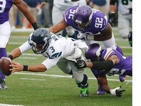 Seattle Seahawks quarterback Russell Wilson (3) dives for a eight-yard touchdown run as Minnesota Vikings cornerback Antone Exum (32) defensive tackle Tom Johnson (92) try to bring him down in the first half of an NFL football game Sunday, Dec. 6, 2015 in Minneapolis.