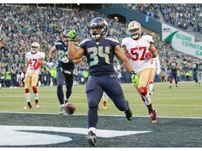 Seattle Seahawks running back Thomas Rawls (34) drops the ball after scoring a touchdown ahead of San Francisco 49ers inside linebacker Michael Wilhoite (57) during the second half of an NFL football game Sunday, Nov. 22, 2015, in Seattle.
