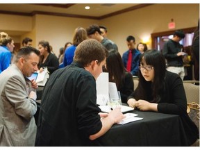 Job seekers fill out applications while attending a career fair.  Statistics Canada's latest labour market figures show that British Columbia's employment growth flattened out last month after experiencing reasonable job gains over 2015.