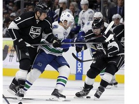 Los Angeles Kings left wing Milan Lucic (17) and defenseman Drew Doughty (8) battle Vancouver Canucks right wing Radim Vrbata (17), of the Czech Republic, for the puck during the first period of an NHL hockey game in Los Angeles, Tuesday, Oct. 13, 2015. (AP Photo/Alex Gallardo)