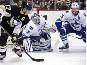 Pittsburgh Penguins' Sidney Crosby (87) looks to get off a shot in front of Vancouver Canucks goalie Ryan Miller (30) and Alexander Edler (23) during the second period of an NHL hockey game in Pittsburgh, Saturday, Jan. 23, 2016.