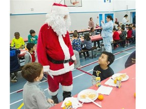 Student James Ferrer (right) greets Santa Claus at Edmonds Community School in Burnaby on Friday.