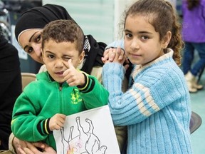 Two Syrian refugee children pose for the camera while their family undergoes medical screening in Beirut, Lebanon, before flying to Canada.