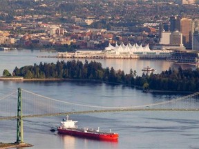 A oil tanker is guided by tug boats as it goes under the Lions Gate Bridge.