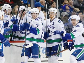 Teammates celebrate with Vancouver Canucks defenseman Ben Hutton (27) after he scored a goal in the second period of an NHL hockey game against the New York Islanders in New York, Sunday, Jan. 17, 2016.