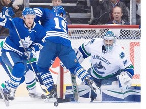 Toronto Maple Leafs centre Leo Komarov (47) battles for the loose puck as Vancouver Canucks goalie Ryan Miller (30) looks on during first period NHL hockey action in Toronto on Saturday, November 14, 2015.