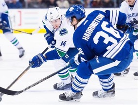 Toronto Maple Leafs defenseman Scott Harrington (36) battles for the loose puck against Vancouver Canucks left wing Alex Burrows (14) during first period NHL hockey action in Toronto on Saturday, November 14, 2015.