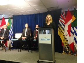 Vancity CEO Tamara Vrooman speaks as Chris Friesen of the Immigrant Services Society of B.C. (left), Vancouver Mayor Gregor Robertson and acting city manager Sadhu Johnston look on at a press conference at Vancouver city hall on Friday.
