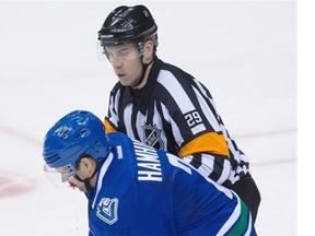 Vancouver Canucks blue-liner Dan Hamhuis is helped off the ice by referee Ian Walsh after being struck in the mouth by the puck during the third period of an NHL game against the visiting New York Rangers at Rogers Arena on Wednesday, Dec. 9, 2015. Hamhuis sustained a facial fracture and will undergo surgery.